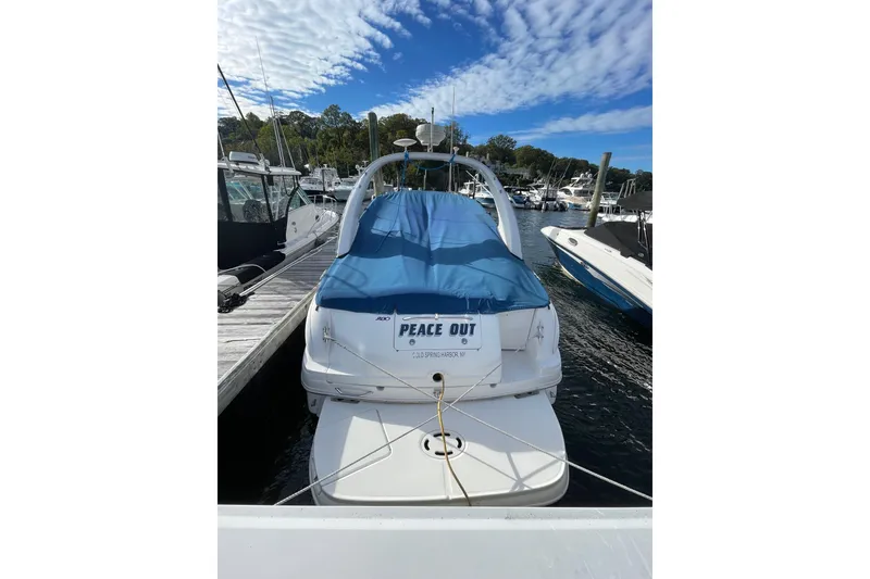 Slide: The Image of 2003 Sea Ray 280 Sundancer docked, covered with blue tarp, under a partly cloudy sky. - 3