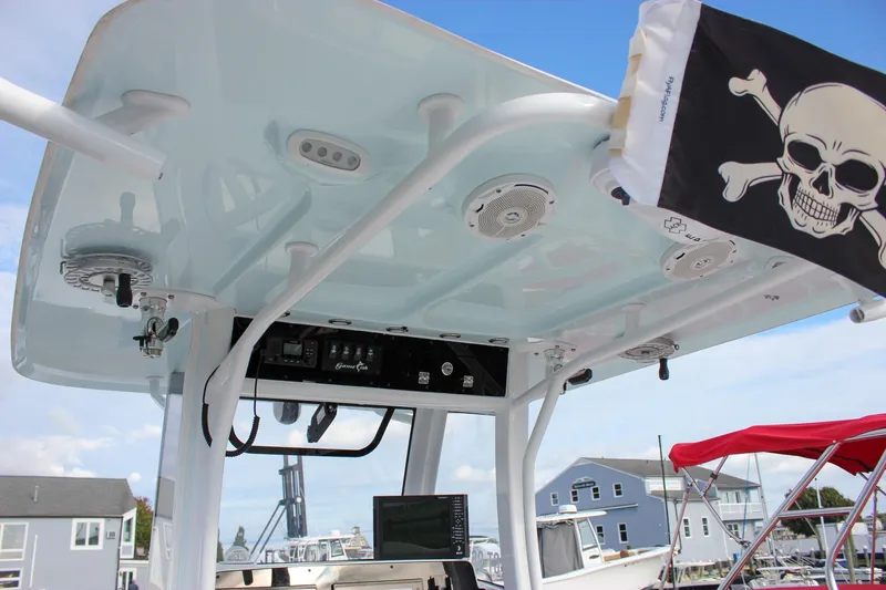 Slide: The Image of 2018 Sea Hunt Gamefish 30 boat with T-top, speakers, and pirate flag in marina setting. - 27