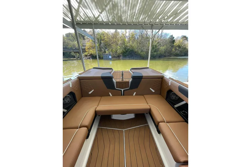 Slide: The Image of 2024 Nautique Super Air Nautique GS22 interior with brown seating and wood-style flooring. - 11