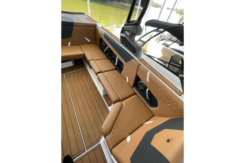 Slide: The Image of 2024 Nautique Super Air Nautique GS22 interior with tan seating and wood flooring. - 14