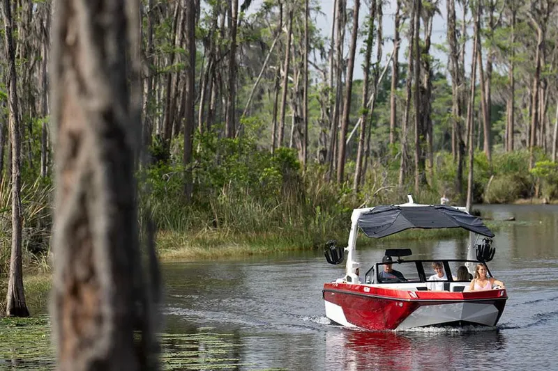 Slide: The Image of Manufacturer Provided Image: 2024 Nautique Super Air Nautique GS22 boat cruising on a forested lake. - 29
