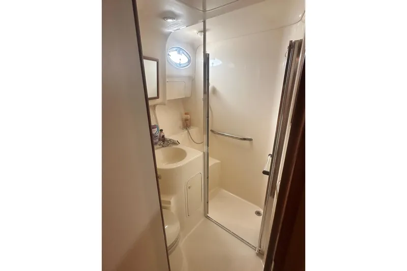 Slide: The Image of 2001 Sea Ray 400 Sedan Bridge bathroom with shower, sink, and porthole window. - 26