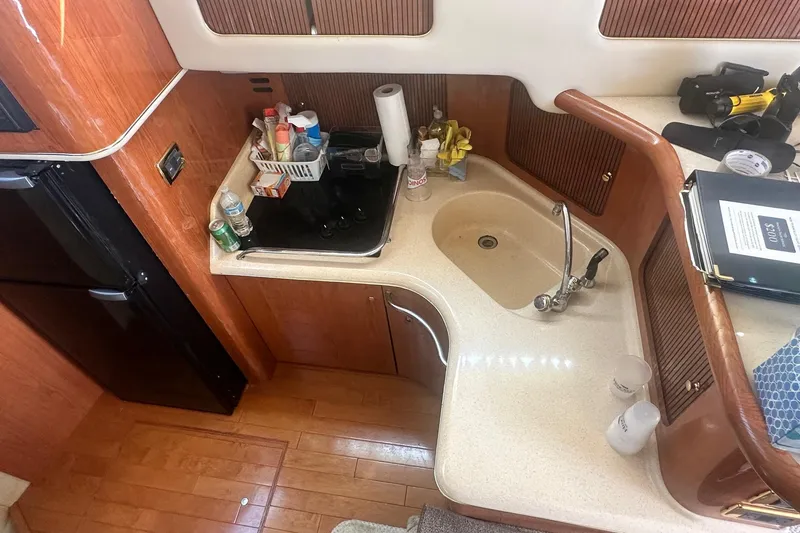 Slide: The Image of 2001 Sea Ray 400 Sedan Bridge kitchen with sink, stove, and wooden cabinetry. - 40