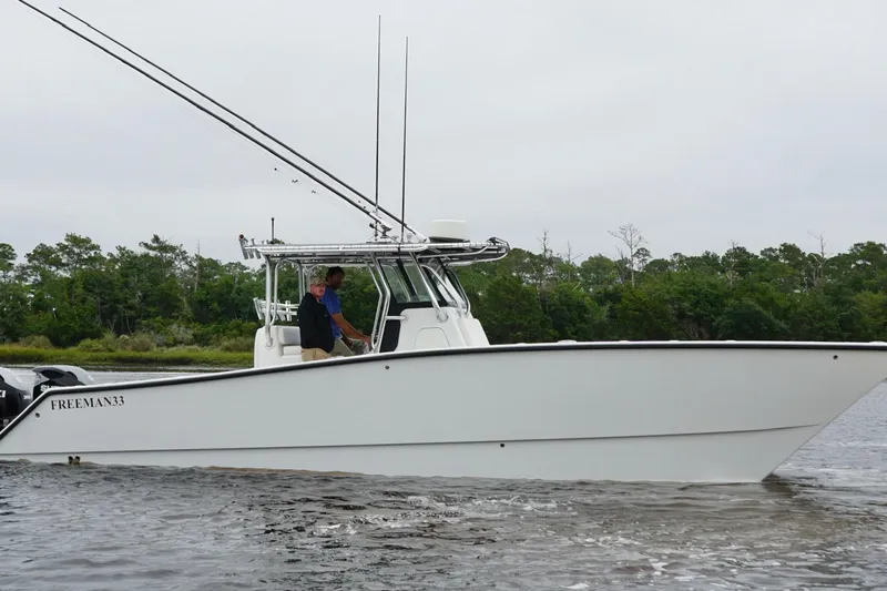 Slide: The Image of 2013 Freeman 33 boat on water with two people, trees in background. - 10