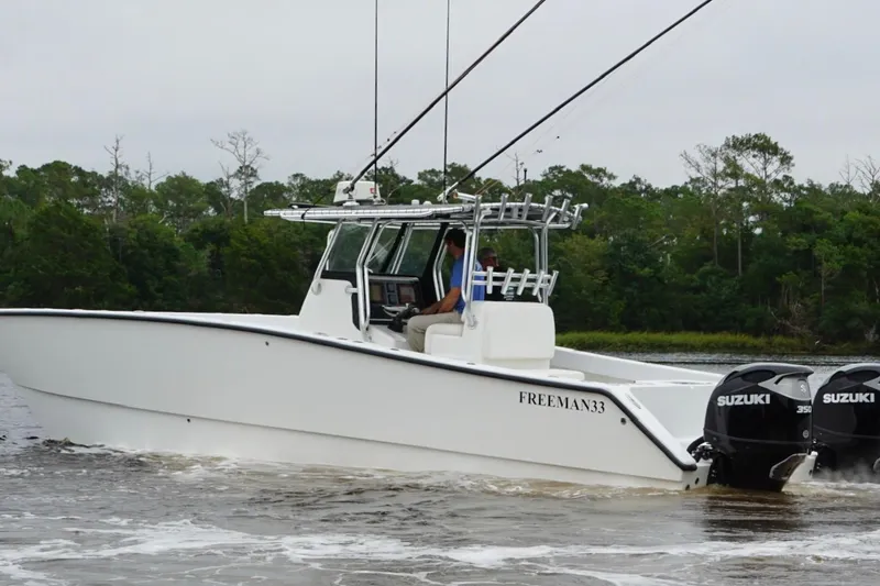 Slide: The Image of A 2013 Freeman 33 boat with dual Suzuki engines cruising on a river. - 11