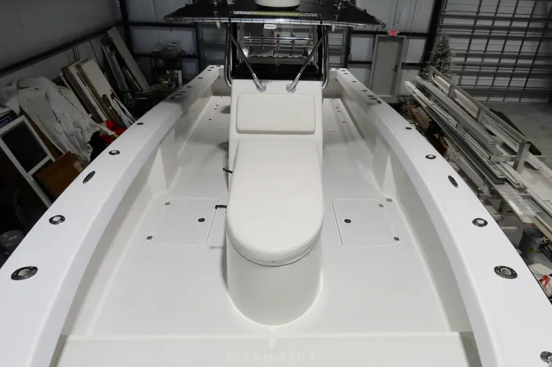 Slide: The Image of 2013 Freeman 33 boat interior with white seating and storage compartments in a warehouse. - 20