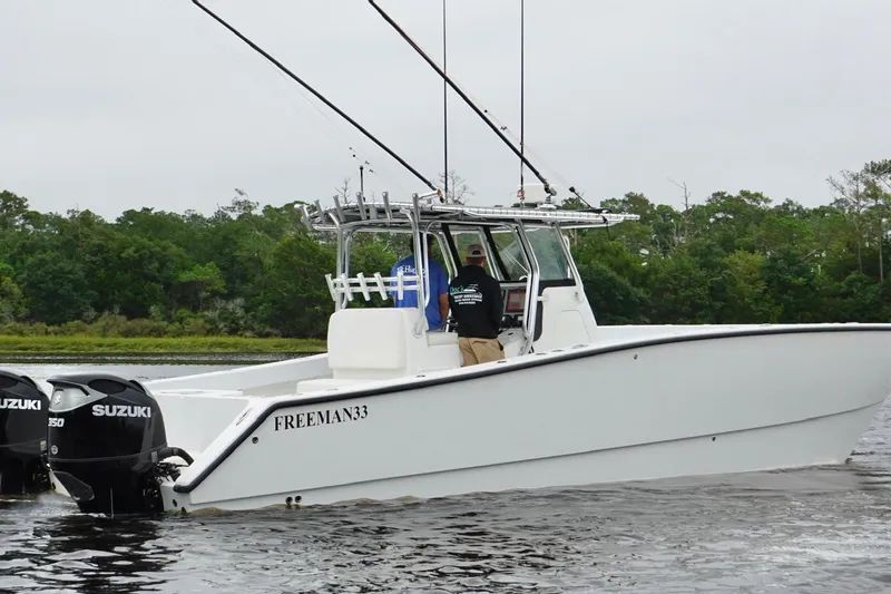 Slide: The Image of 2013 Freeman 33 boat with dual Suzuki engines on a calm waterway. - 4