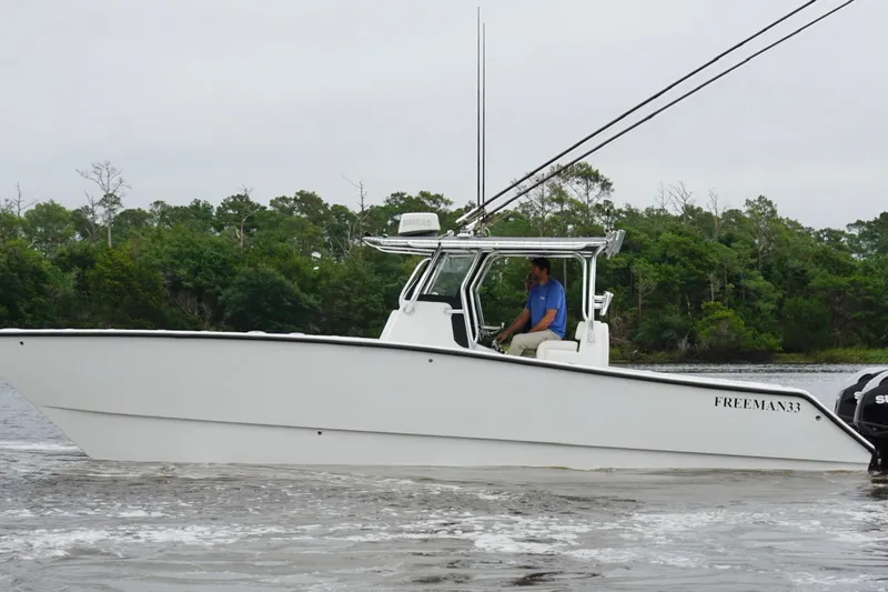 Slide: The Image of 2013 Freeman 33 boat cruising on a river with lush green trees in the background. - 5