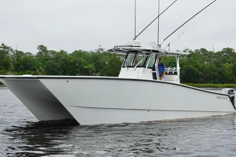 Slide: The Image of 2013 Freeman 33 boat cruising on a calm river with lush green trees in the background. - 6