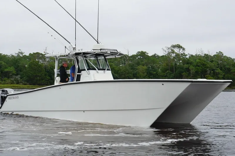 Slide: The Image of 2013 Freeman 33 boat cruising on a calm river with lush green trees in the background. - 7