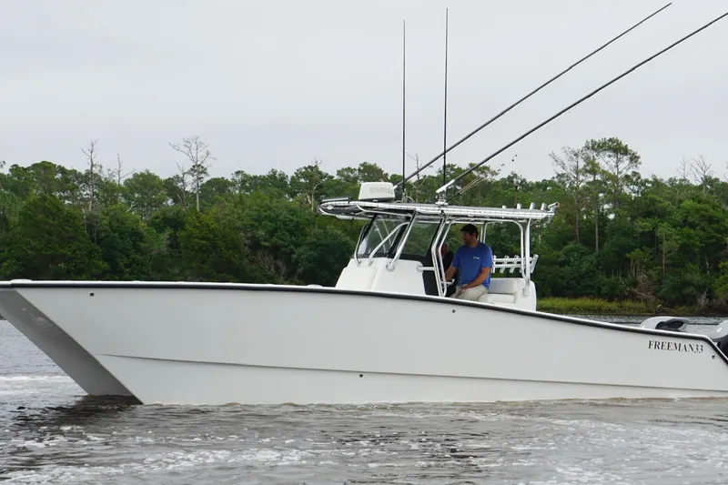 Slide: The Image of 2013 Freeman 33 boat cruising on a river with lush green trees in the background. - 8