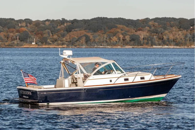 The Image of 2007 Hunt Surfhunter 29 boat cruising on a calm lake with forested shoreline. - 0