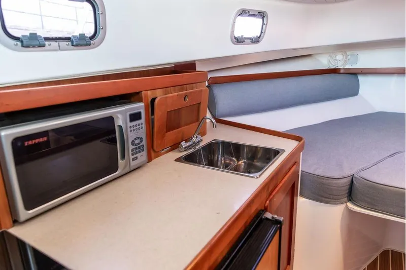 Slide: The Image of 2007 Hunt Surfhunter 29 interior with kitchenette, sink, microwave, and cozy seating area. - 36