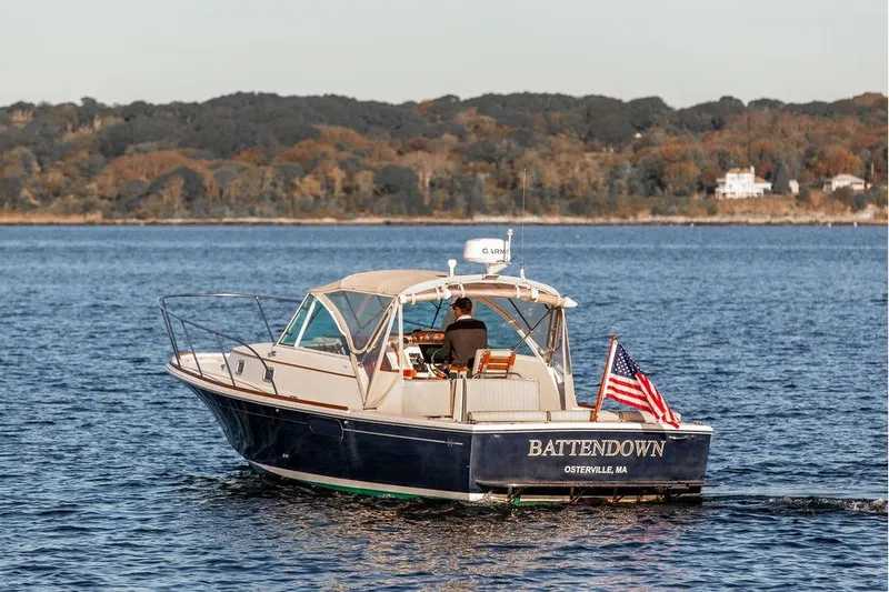 Slide: The Image of 2007 Hunt Surfhunter 29 boat cruising on a calm lake with American flag. - 6