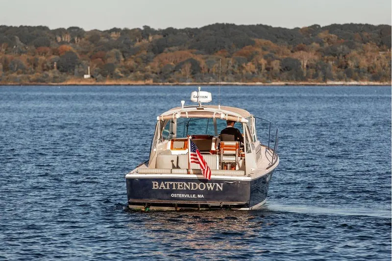 Slide: The Image of 2007 Hunt Surfhunter 29 boat cruising on a calm lake with forested shoreline. - 7