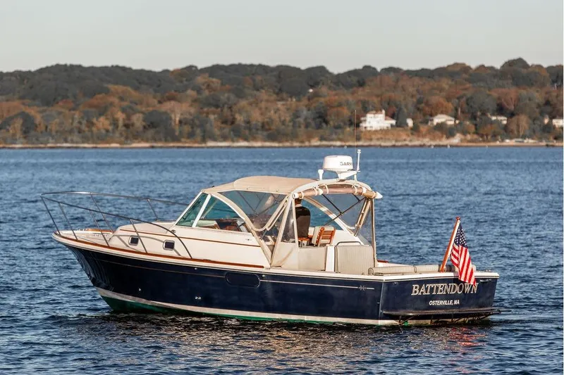 Slide: The Image of 2007 Hunt Surfhunter 29 boat on water, American flag, scenic background. - 1