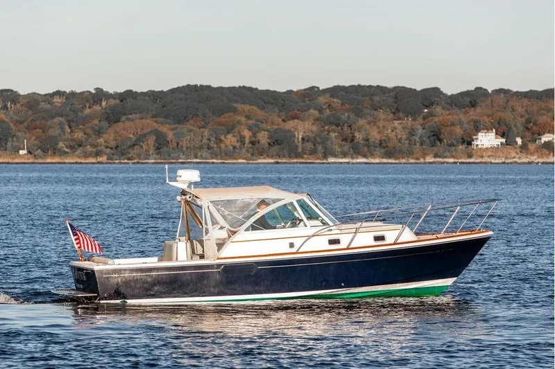 Slide: The Image of 2007 Hunt Surfhunter 29 boat cruising on a calm lake with scenic forest backdrop. - 11