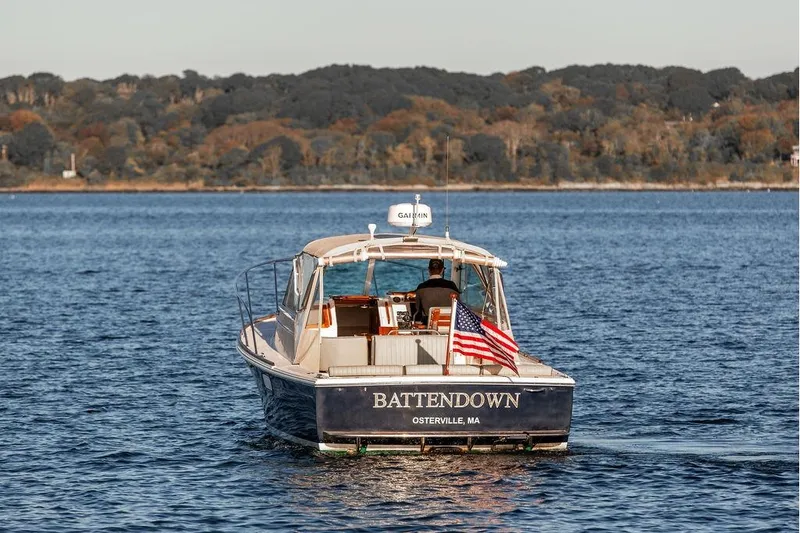Slide: The Image of 2007 Hunt Surfhunter 29 boat on water, American flag, scenic background. - 2