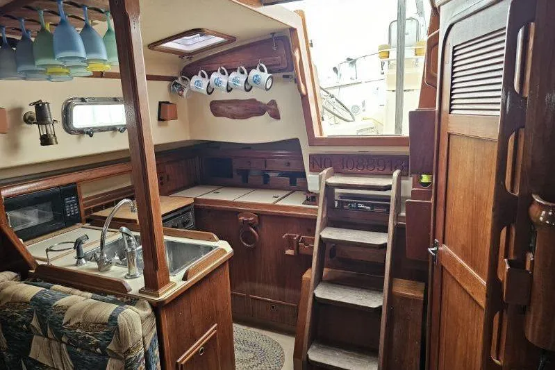 Slide: The Image of Interior of 1999 Island Packet 350 sailboat with wooden cabinetry and kitchen amenities. - 2