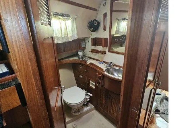 Slide: The Image of 1999 Island Packet 350 yacht bathroom with wooden cabinetry, sink, and toilet. - 22