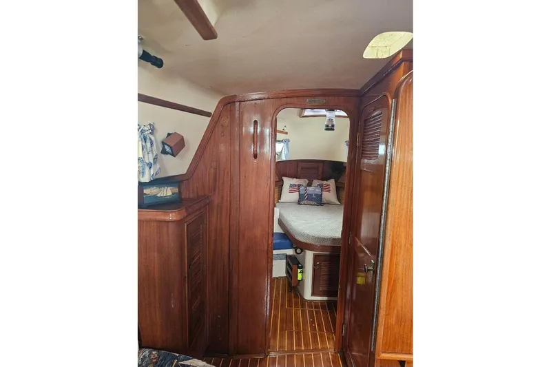 Slide: The Image of Interior of 1999 Island Packet 350 sailboat, featuring cozy wooden cabin and bed. - 24