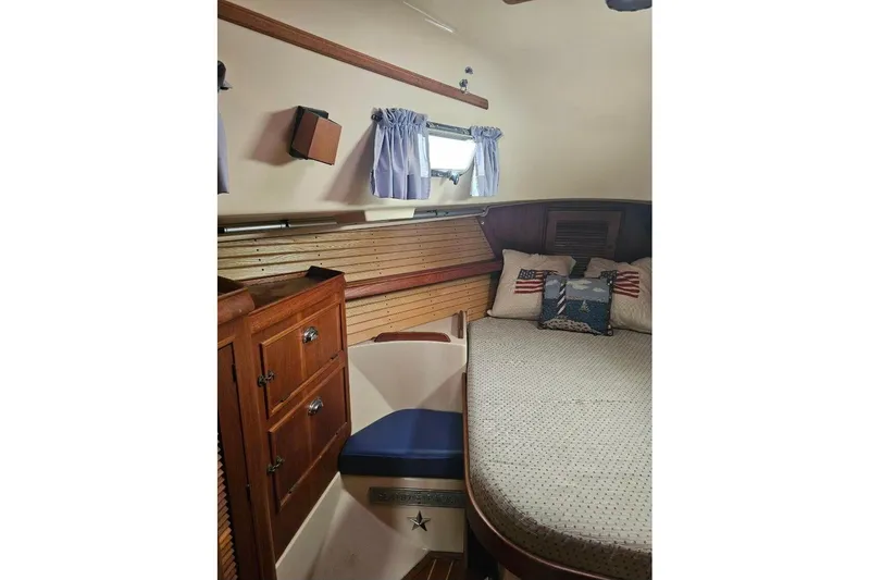 Slide: The Image of 1999 Island Packet 350 cabin interior with cozy bed, wooden cabinets, and nautical decor. - 26