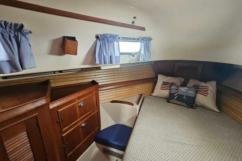 Slide: The Image of Cozy cabin interior of 1999 Island Packet 350 sailboat with wooden cabinetry and nautical-themed pillows. - 29