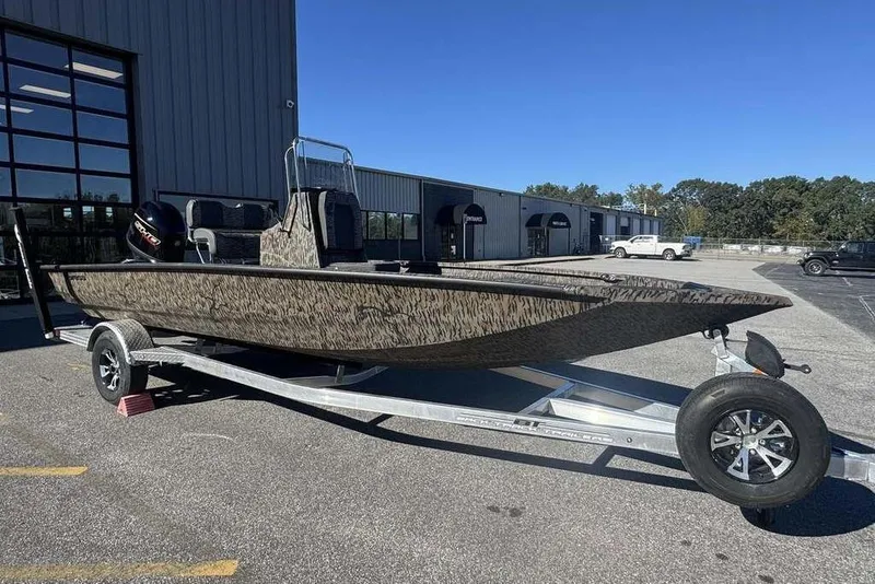 Slide: The Image of 2026 Xpress H20B Bay boat on trailer, parked outdoors under clear blue sky. - 1