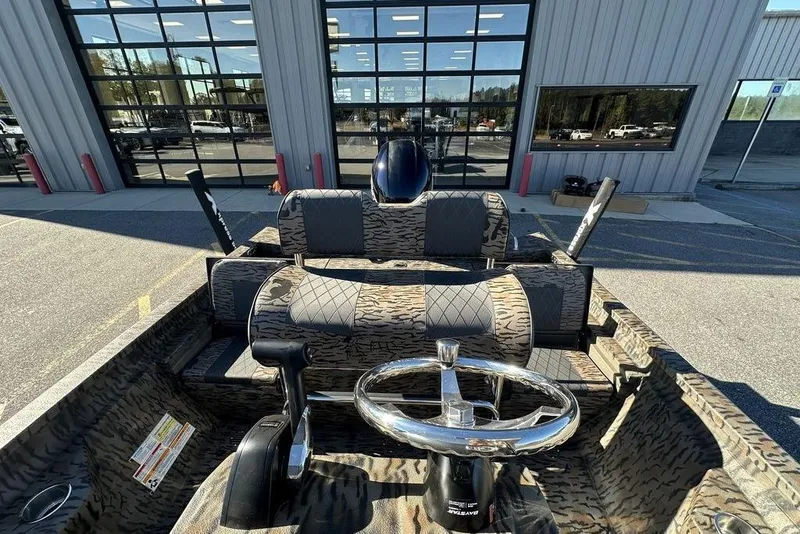 Slide: The Image of 2026 Xpress H20B Bay boat interior with camouflage seating and steering wheel, outside dealership. - 4