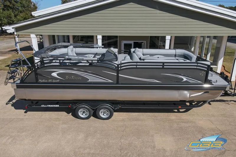 Slide: The Image of 2026 JC 25 Neptoon LG pontoon boat on trailer, parked outside a building. - 21