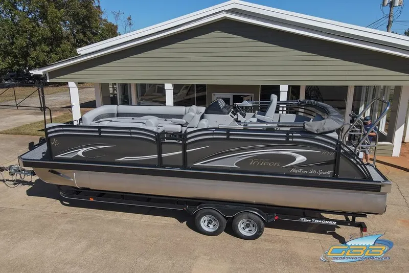 Slide: The Image of 2026 JC 25 Neptoon LG pontoon boat on trailer, parked outside a building. - 6