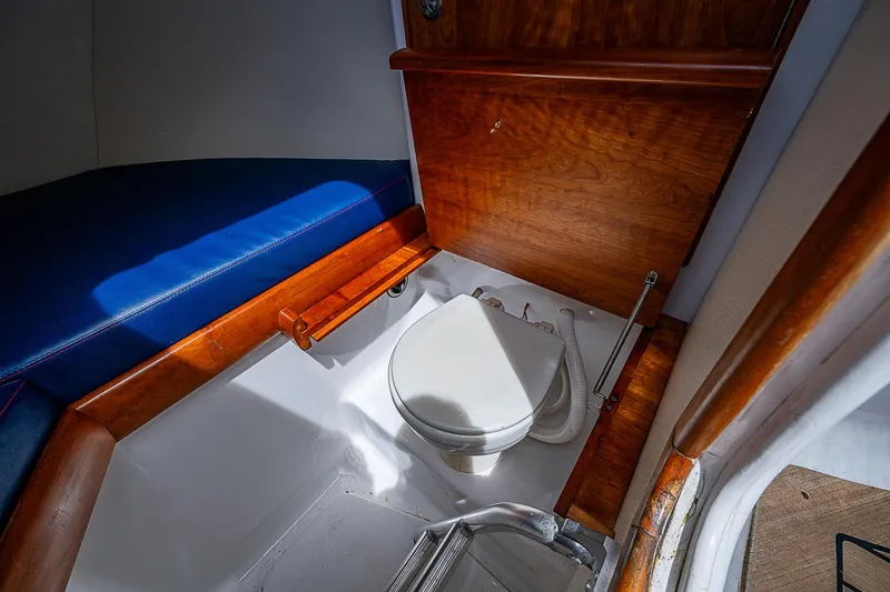 Slide: The Image of Interior of 2011 Winter Custom Yachts 29, featuring a compact marine toilet and wooden accents. - 14