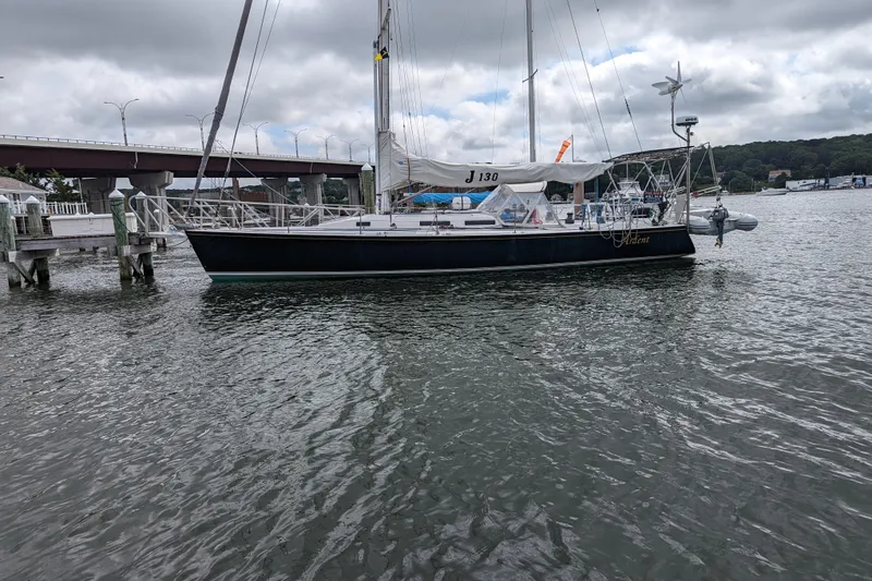 Slide: The Image of Sailboat J/130 from 1993 docked near a bridge on a cloudy day. - 2
