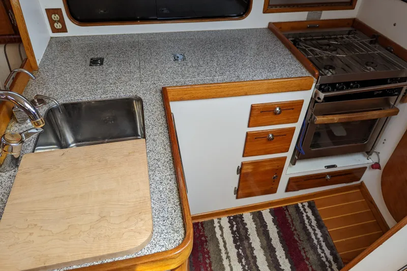 Slide: The Image of Galley kitchen in 1993 J Boats J/130 sailboat with sink, stove, and wooden cabinetry. - 26