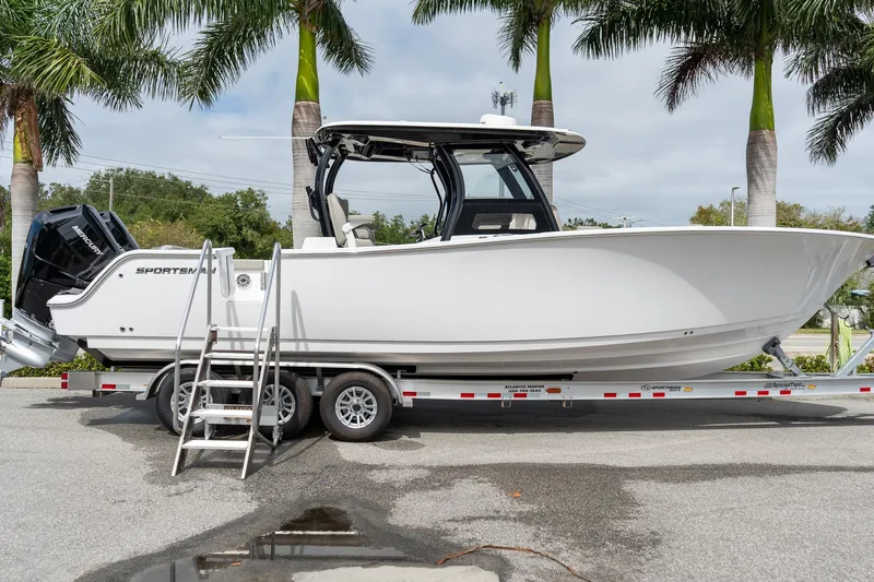 Slide: The Image of 2025 Sportsman Open 322 Center Console boat on trailer, parked under palm trees. - 19