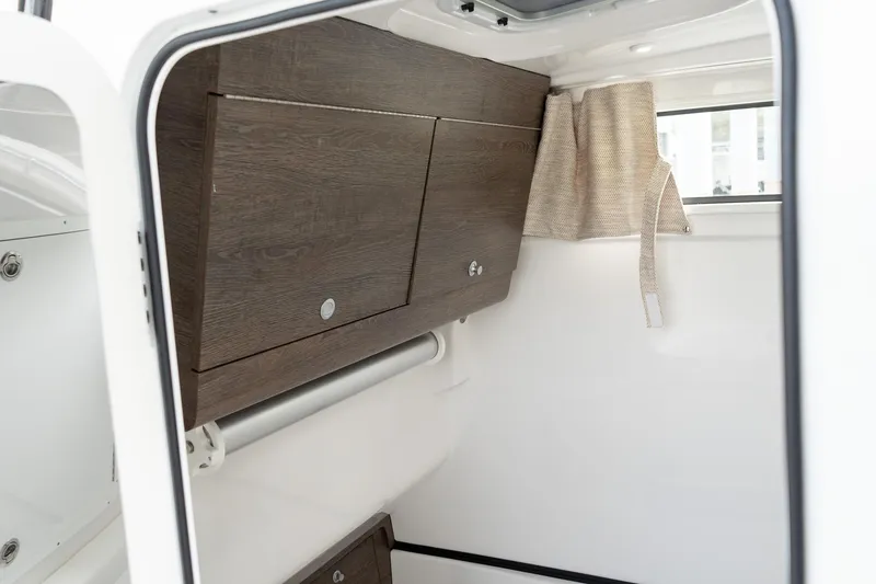 Slide: The Image of 2025 Sportsman Open 322 Center Console interior with wooden cabinets and window curtain. - 49