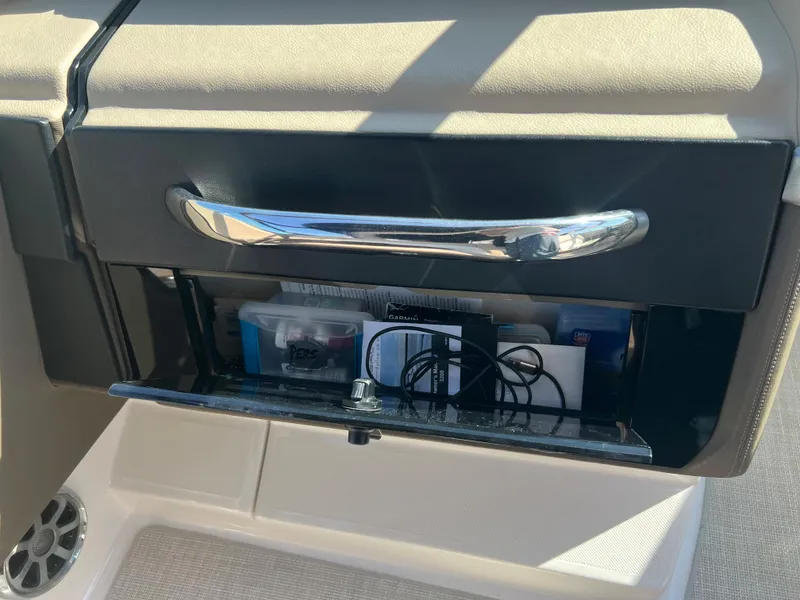 Slide: The Image of Open glove compartment of a 2013 Regal 3200 Bowrider boat with various items inside. - 12