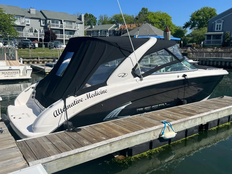 Slide: The Image of 2013 Regal 3200 Bowrider boat docked with black canopy. - 3