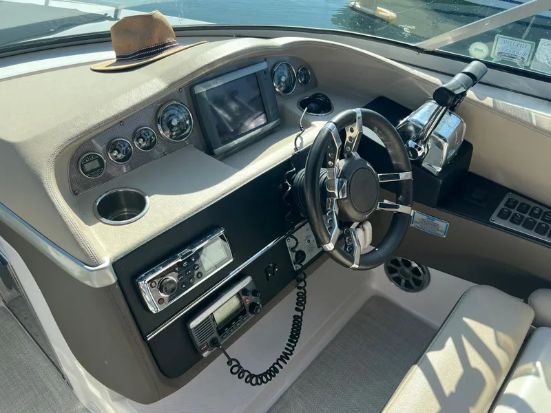 Slide: The Image of 2013 Regal 3200 Bowrider dashboard with steering wheel, controls, and hat. - 7