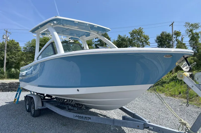 The Image of 2026 Robalo R257 Dual Console boat on trailer, blue and white design, sunny day. - 0