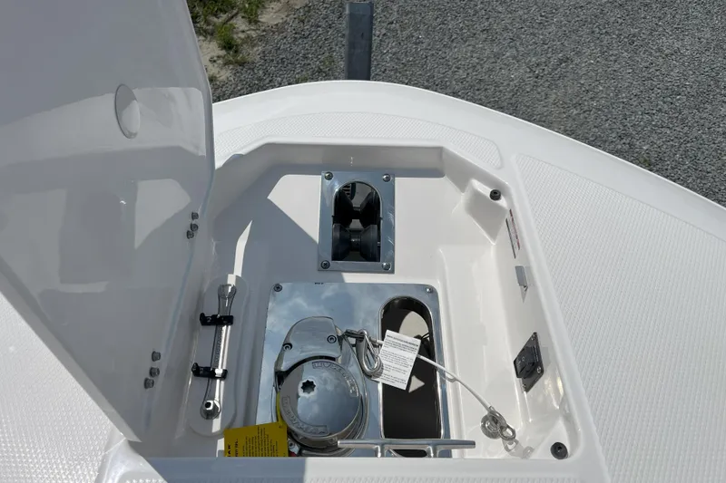 Slide: The Image of 2026 Robalo R257 Dual Console anchor compartment with open hatch, showcasing storage and hardware. - 16