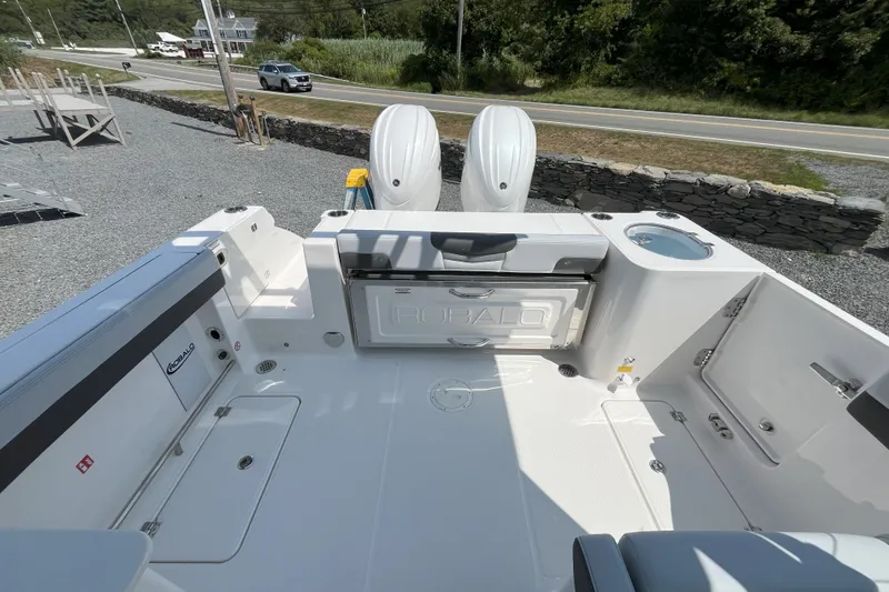Slide: The Image of 2026 Robalo R257 Dual Console boat interior with seating and storage, parked on gravel. - 2