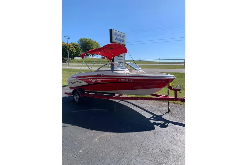 The Image of 2014 Tahoe Q5i Sport boat with red canopy on trailer, parked outdoors. - 1