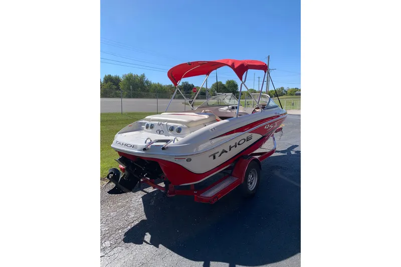 Slide: The Image of 2014 Tahoe Q5i Sport boat with red canopy on trailer, parked outdoors. - 4