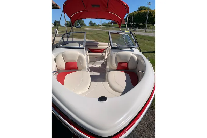Slide: The Image of 2014 Tahoe Q5i Sport boat with red and white interior, parked on grass. - 7