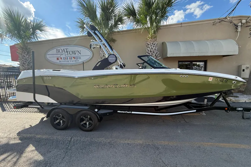 The Image of 2023 MasterCraft NXT24 boat on trailer, parked outside Boat Town dealership. - 1