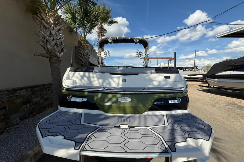 Slide: The Image of 2023 MasterCraft NXT24 boat rear view with swim platform, parked under a clear blue sky. - 7