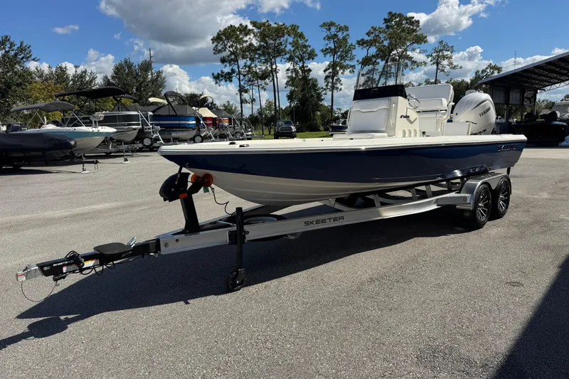 Slide: The Image of 2026 Skeeter SX221 boat on trailer in outdoor showroom under blue sky. - 7