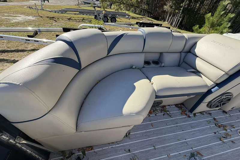 Slide: The Image of 2017 Berkshire 23 boat interior with beige seating and cup holders. - 16