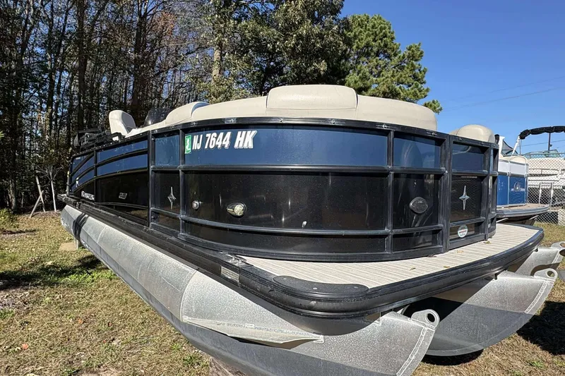 Slide: The Image of 2017 Berkshire 23 pontoon boat on grass, surrounded by trees and clear blue sky. - 4